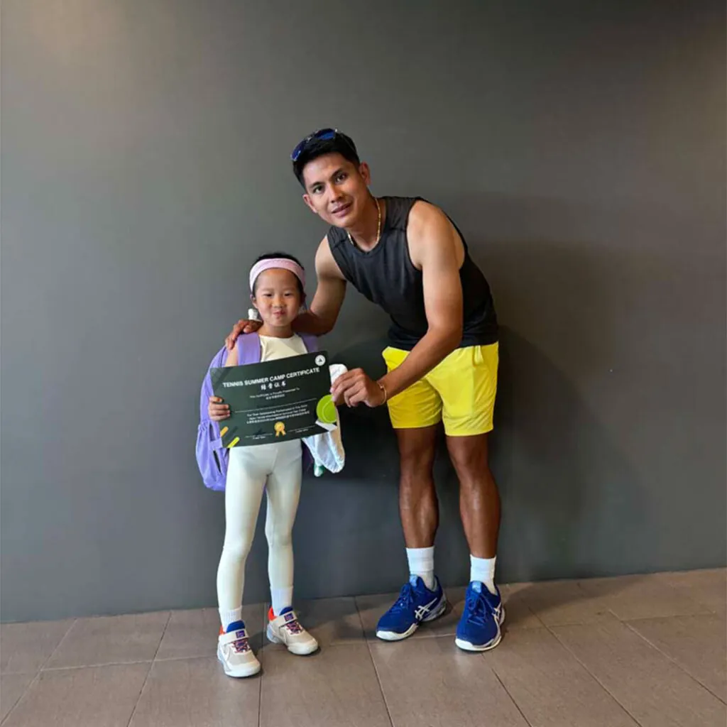 A young student showing off her achievement certificate beside her coach