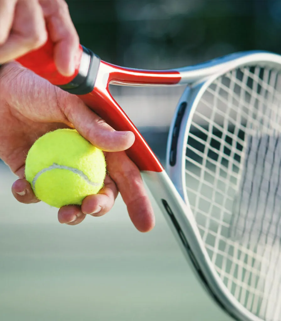 A close-up of a hand holding a ball against the racquet throat before serving