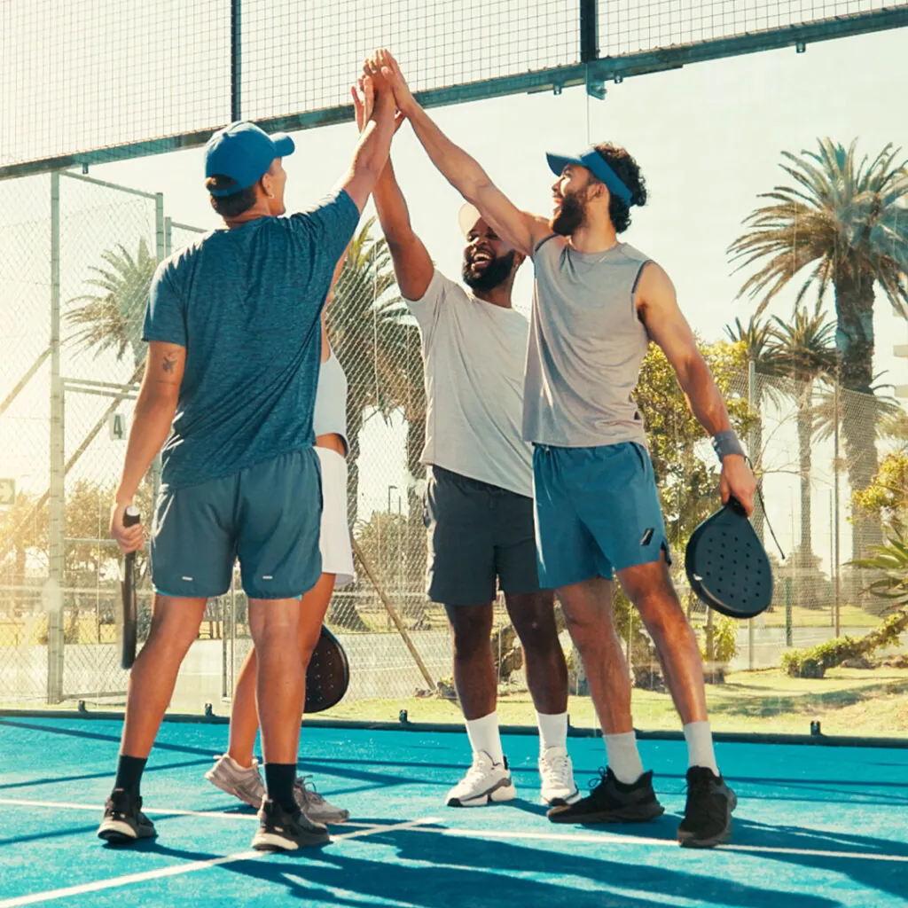Three players high-fiving at the net after a match