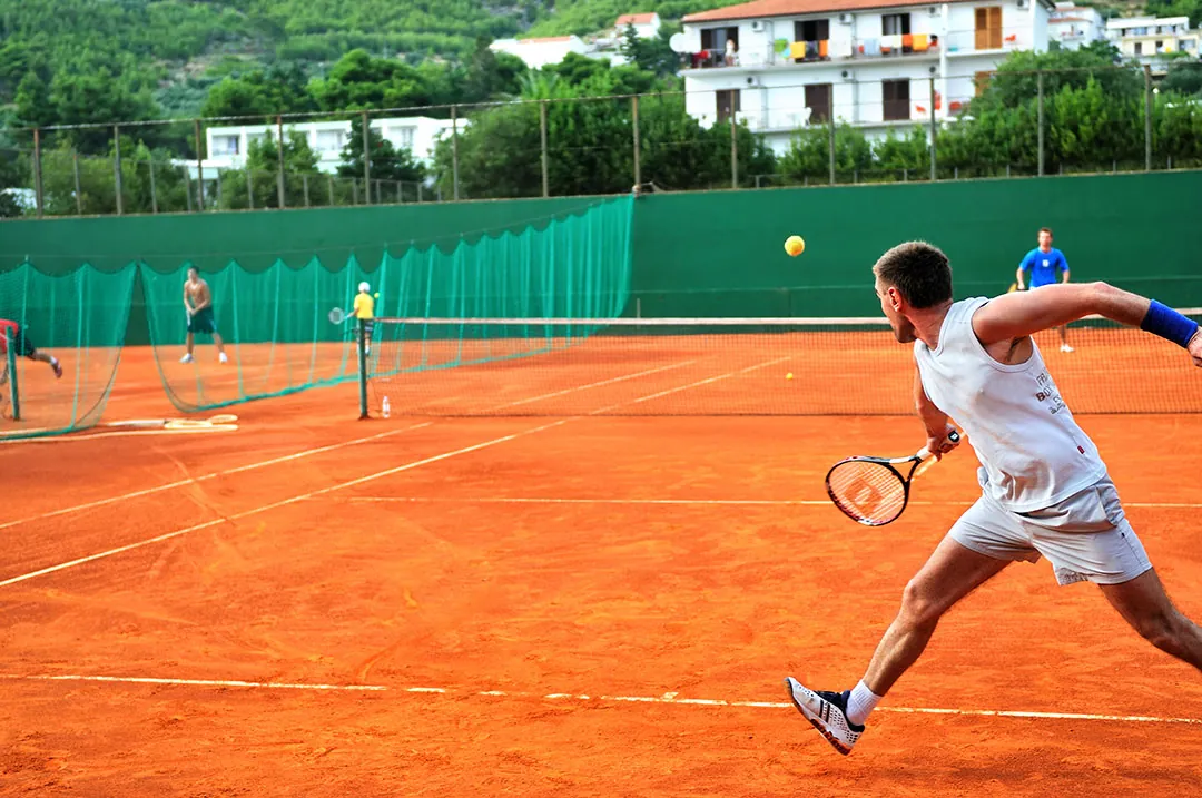 A player stretching for a forehand during a match on a clay court