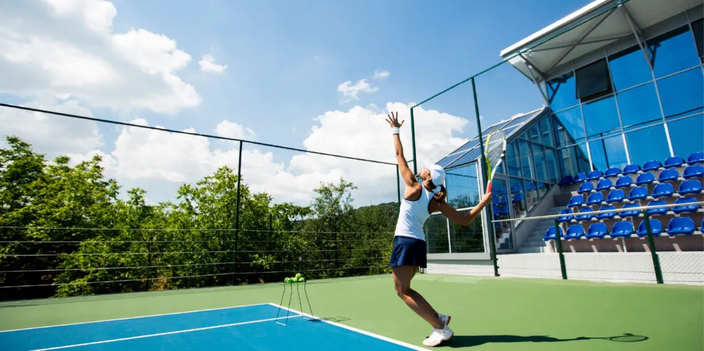 A player reaching up to serve on an outdoor court