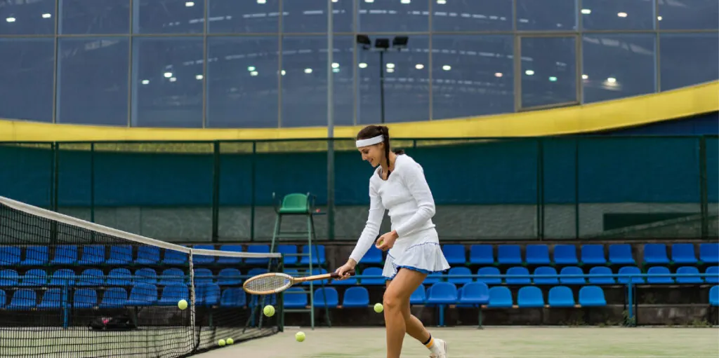 A player following through on a backhand under the covered court lights