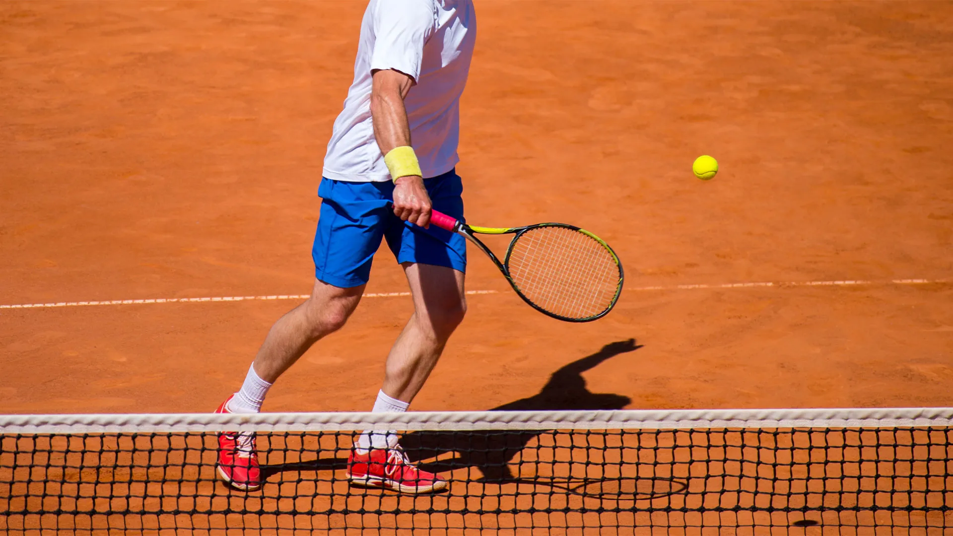 A player volleying at the net on a clay court