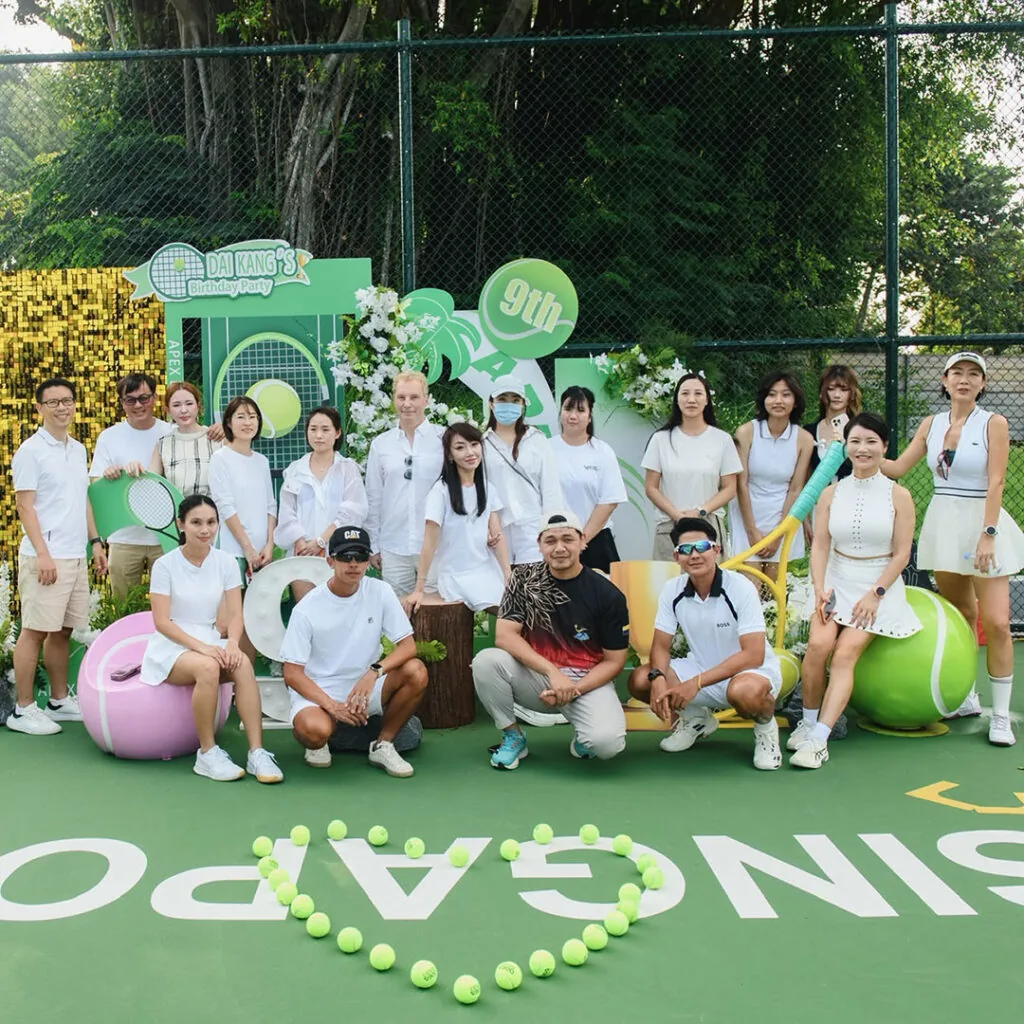 The whole academy posed in front of the decorated backdrop, SINGAPORE spelled in tennis balls at their feet