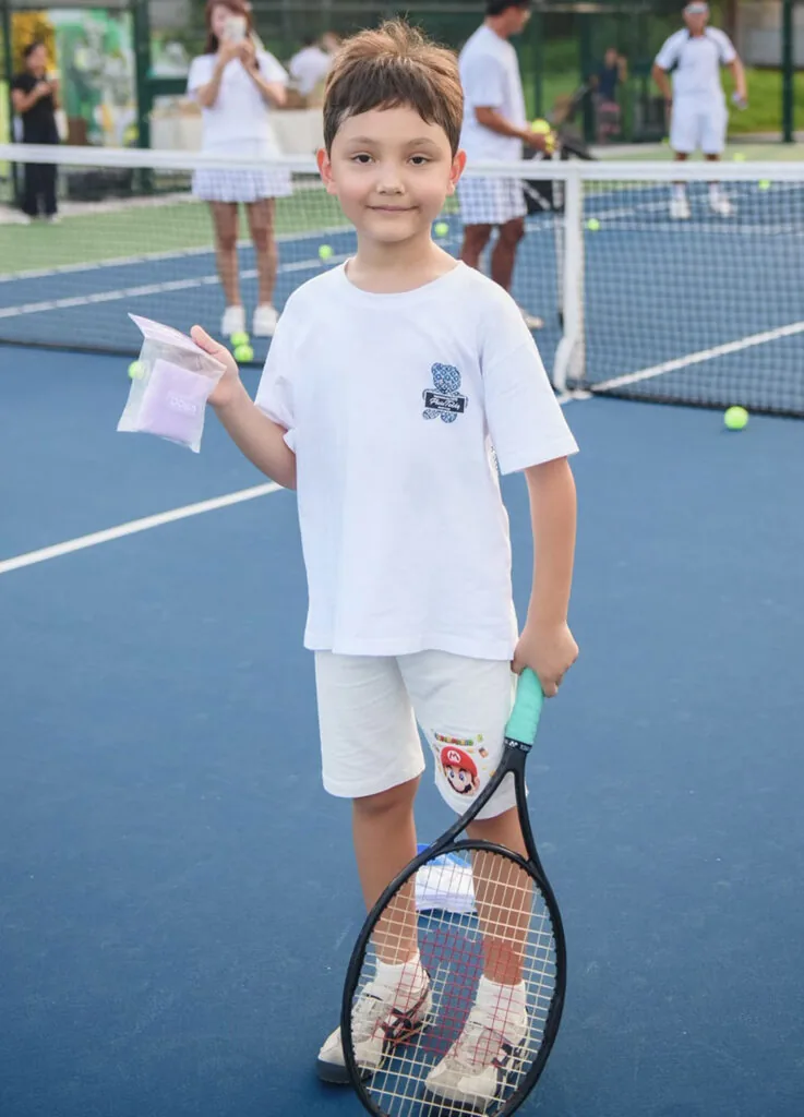A smiling junior holding his racquet and a prize bag
