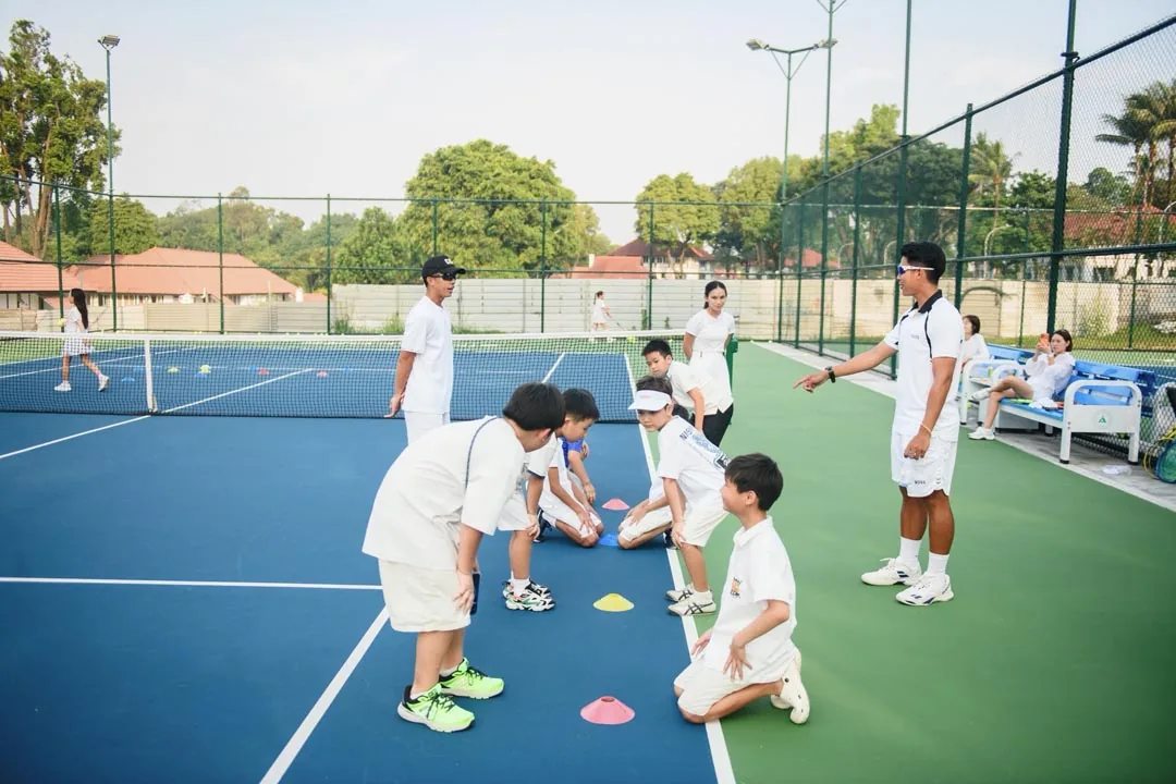 A coach crouching beside young players around coloured spot markers