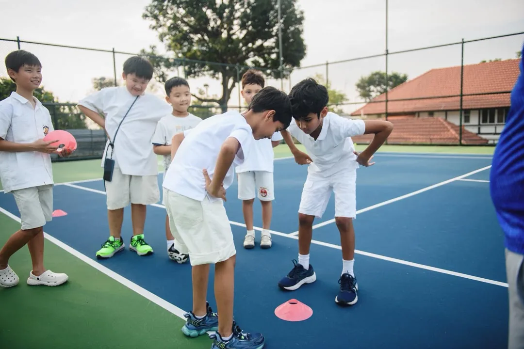 Juniors bending into a warm-up exercise around a marker