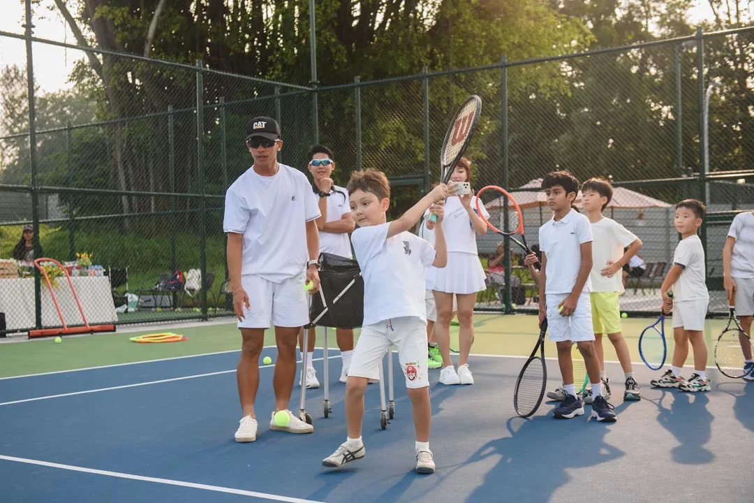 A boy reaching up to strike while the coaches look on