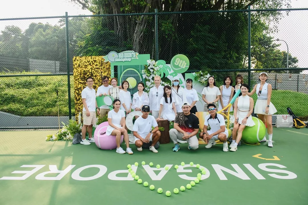 Coaches and staff in white, grouped in front of the decorated backdrop