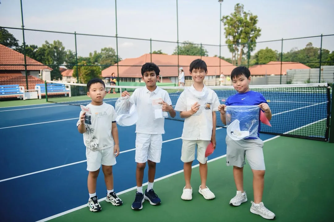 Four boys standing at the net, holding their prize bags